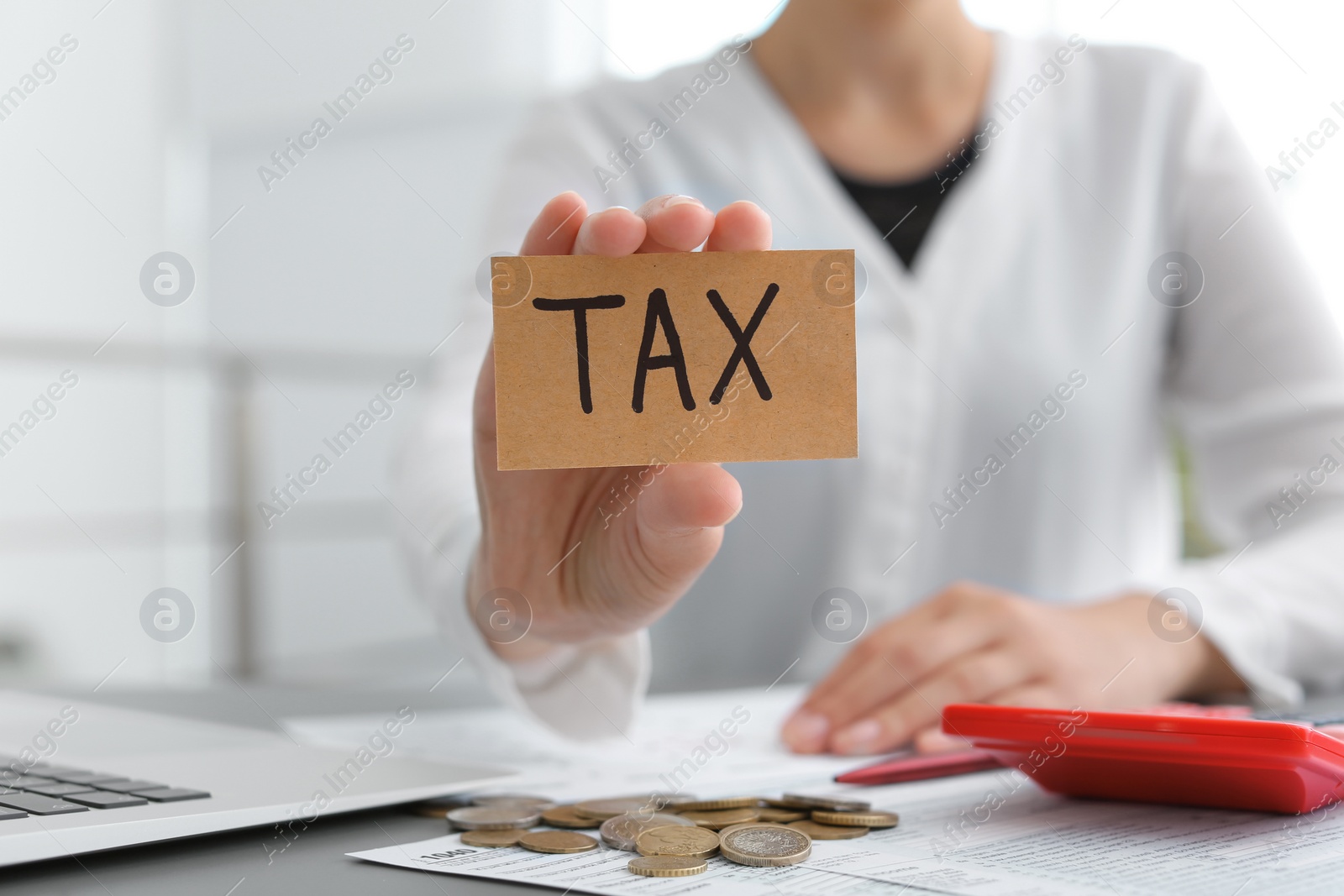 Photo of Woman holding card with word TAX at table
