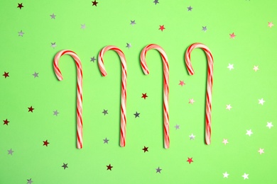 Photo of Flat lay composition with tasty candy canes on color background