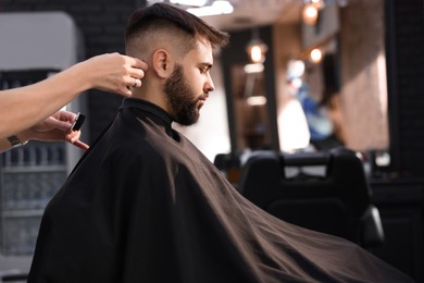 Professional hairdresser working with client in barbershop