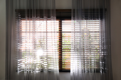Photo of Window with beautiful curtains and blinds, closeup