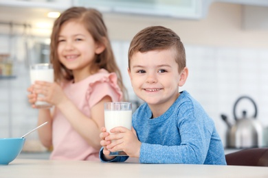 Photo of Cute little kids drinking milk in kitchen