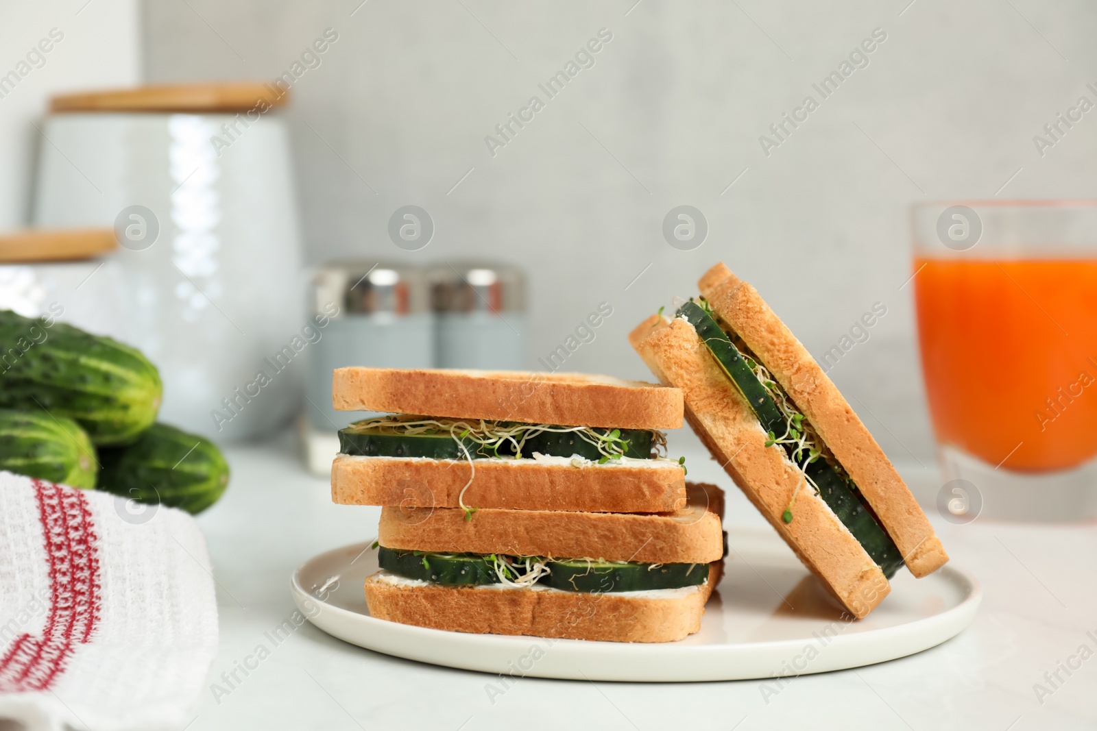 Photo of Tasty sandwiches with cucumber, cream cheese and microgreens on white table, closeup