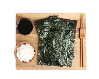 Wooden board with dry nori sheets, rice, soy sauce and chopsticks on white background, top view