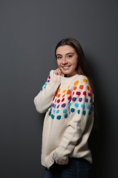 Photo of Beautiful young woman in warm sweater on dark background