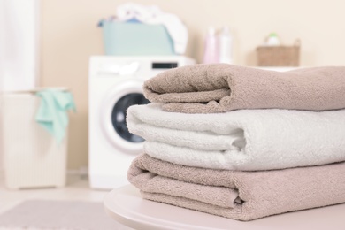 Stack of clean towels on table in laundry room. Space for text