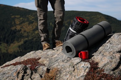 Photo of Tourist with sleeping bag, mat and cup on mountain peak, closeup