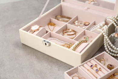 Jewelry boxes with many different accessories on light grey table, closeup