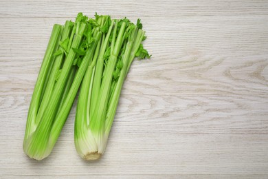 Photo of Fresh green celery bunches on white wooden table, top view. Space for text