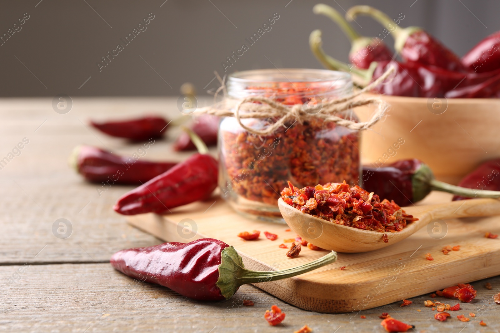 Photo of Chili pepper flakes and pods on wooden table, closeup. Space for text