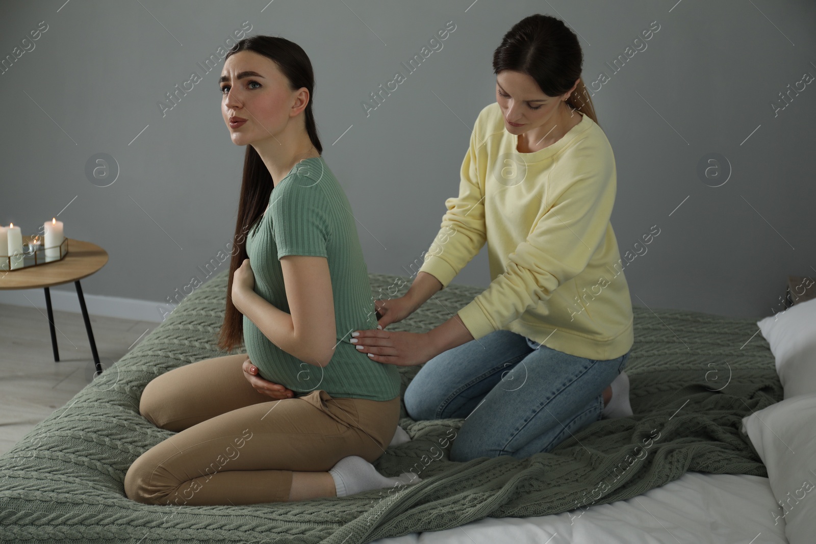 Photo of Doula massaging pregnant woman in bedroom. Preparation for child birth