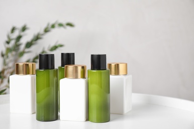 Photo of Mini bottles with cosmetic products on white table. Space for text