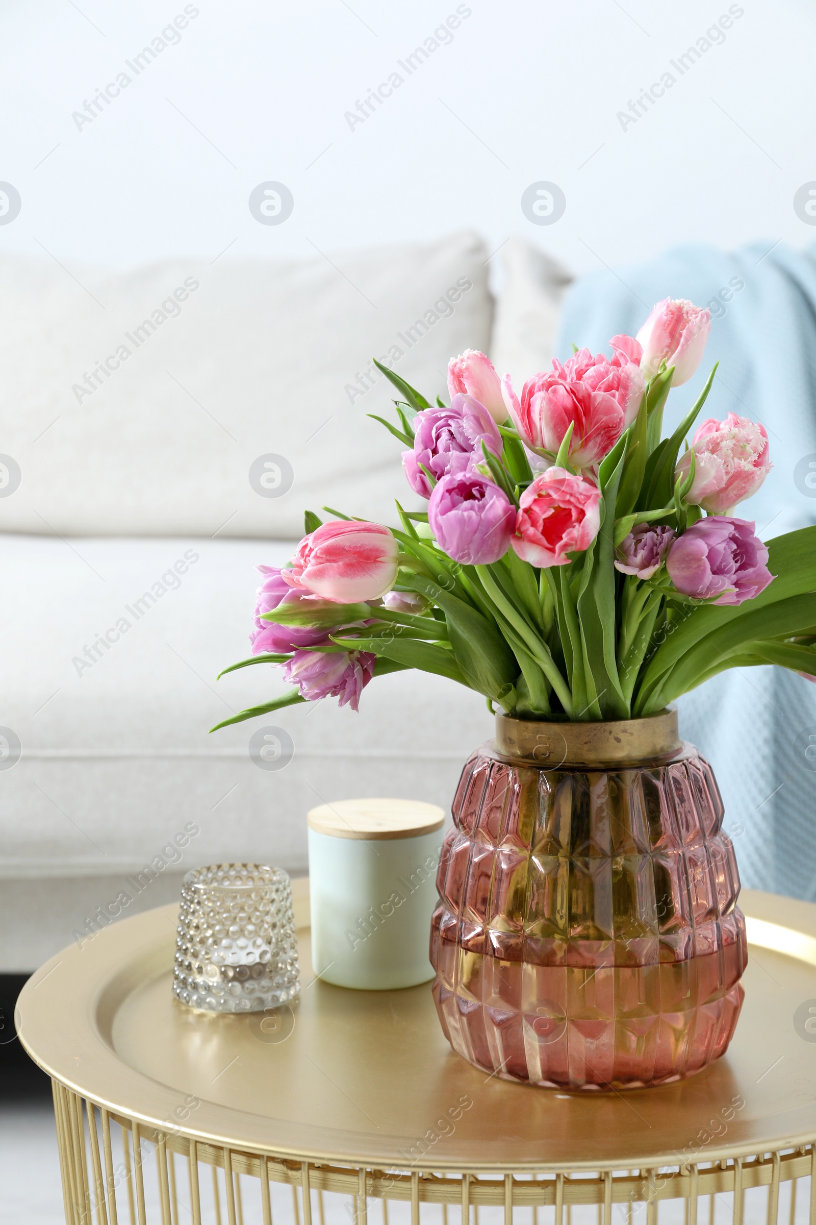 Photo of Beautiful bouquet of colorful tulip flowers on coffee table in room