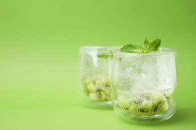 Refreshing drink with kiwi and mint on light green background, closeup. Space for text