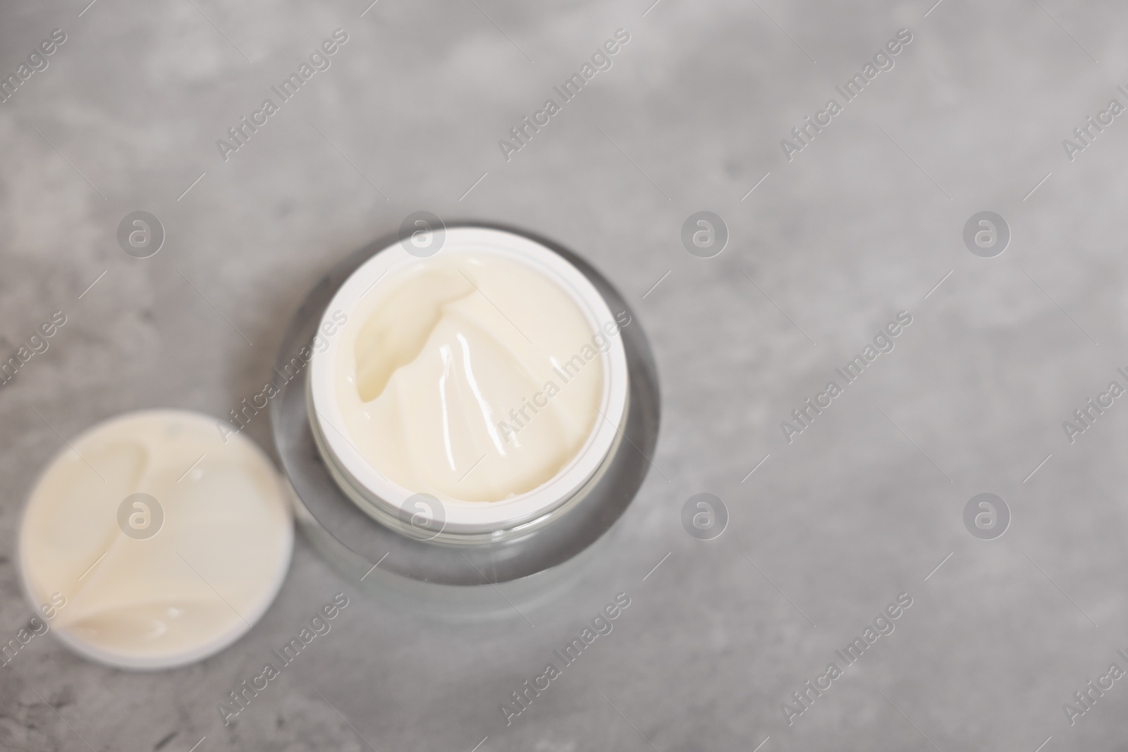 Photo of Body cream on grey table, above view. Space for text