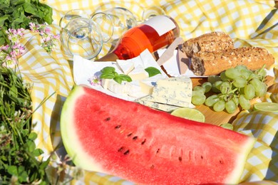 Photo of Picnic blanket with delicious food and wine on green grass outdoors, closeup