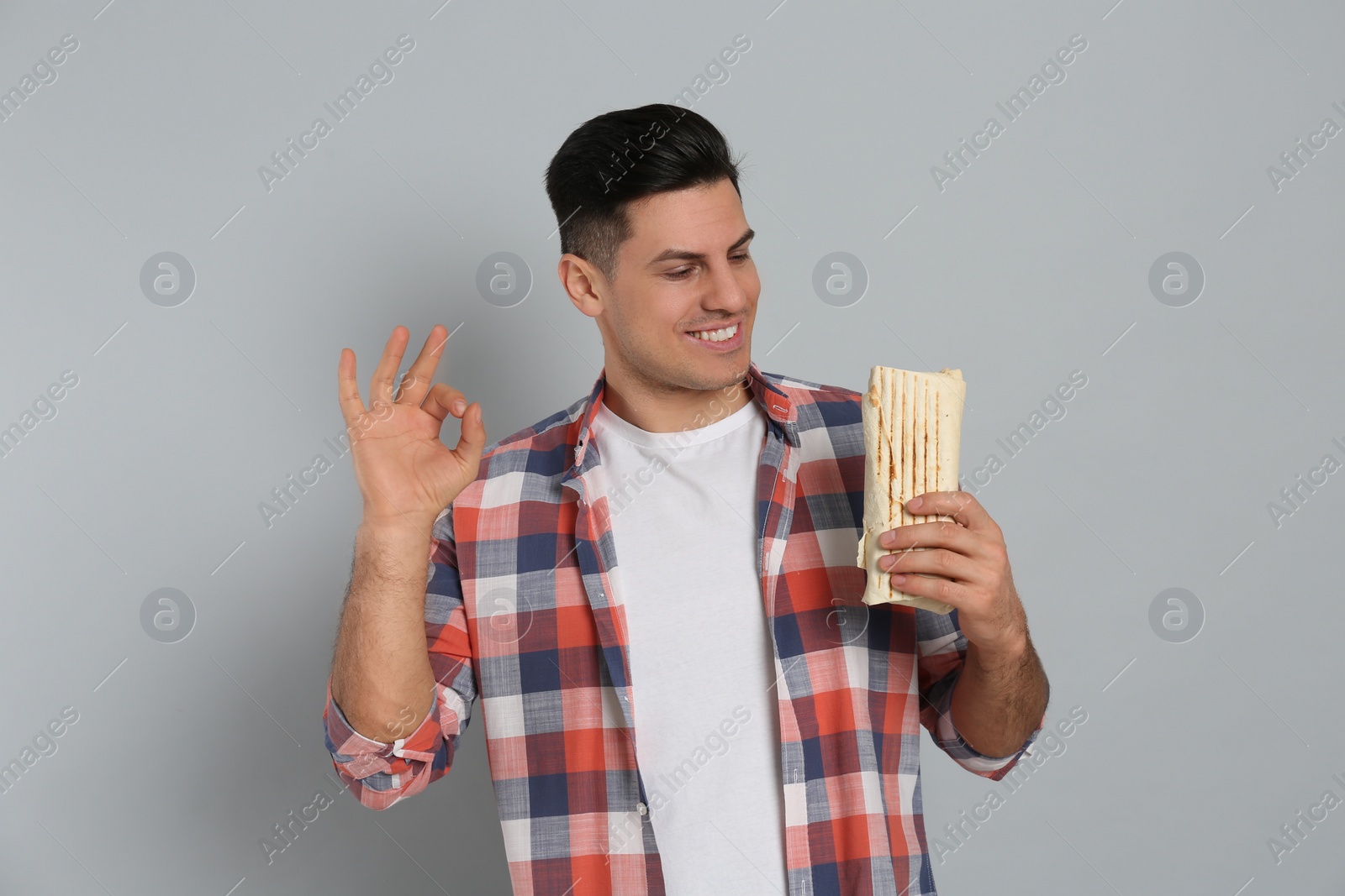 Photo of Man with delicious shawarma on grey background