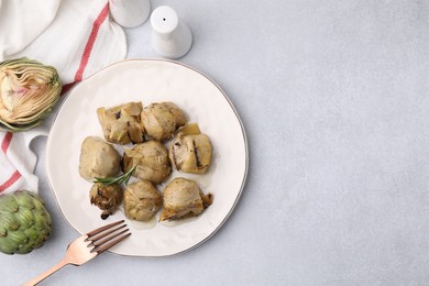 Delicious pickled artichokes with rosemary served on light grey table, flat lay. Space for text