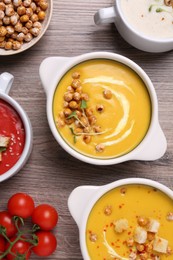 Different tasty cream soups on wooden table, flat lay