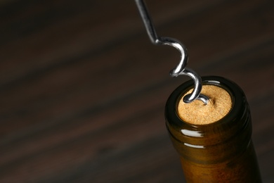 Photo of Bottle of wine and corkscrew on dark background, space for text