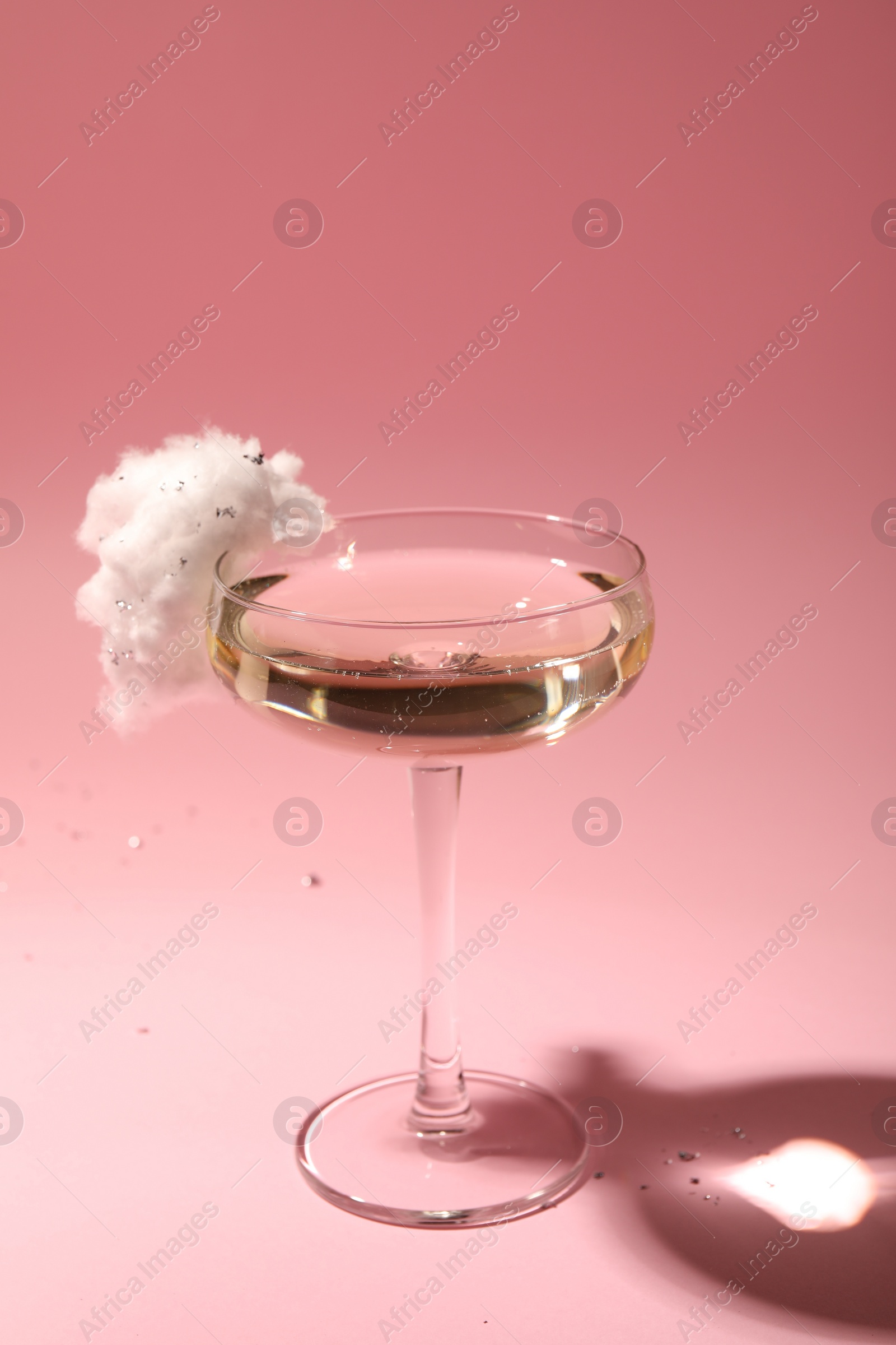 Photo of Tasty cocktail in glass decorated with cotton candy on pink background