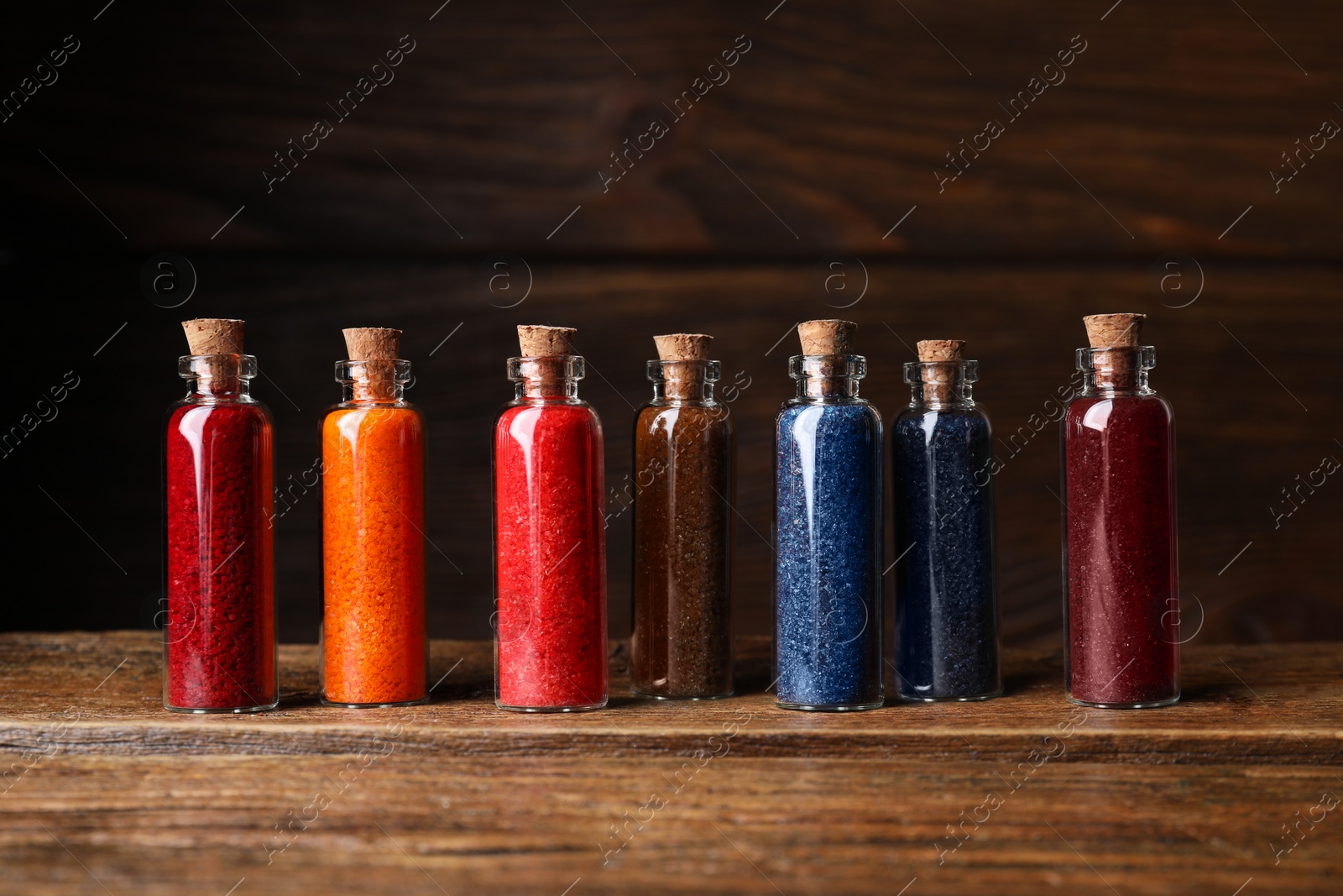 Photo of Glass bottles with different food coloring on wooden table