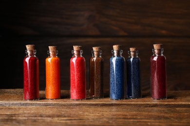 Photo of Glass bottles with different food coloring on wooden table