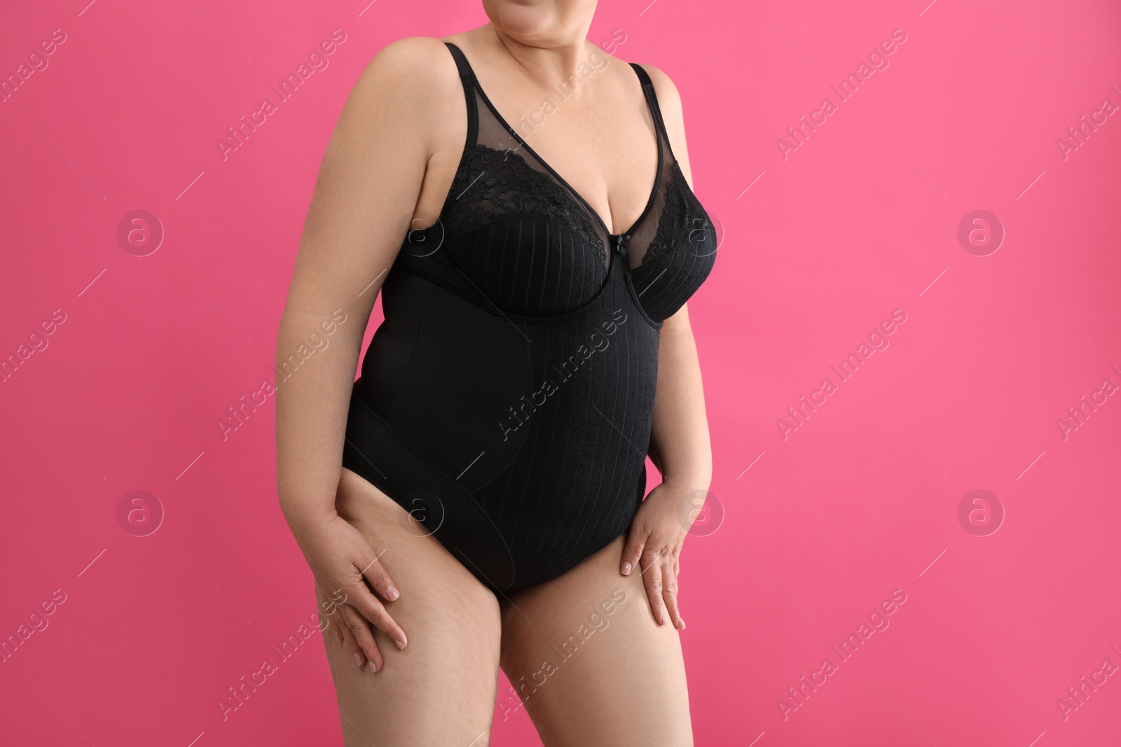 Photo of Overweight woman in black underwear on pink background, closeup. Plus-size model