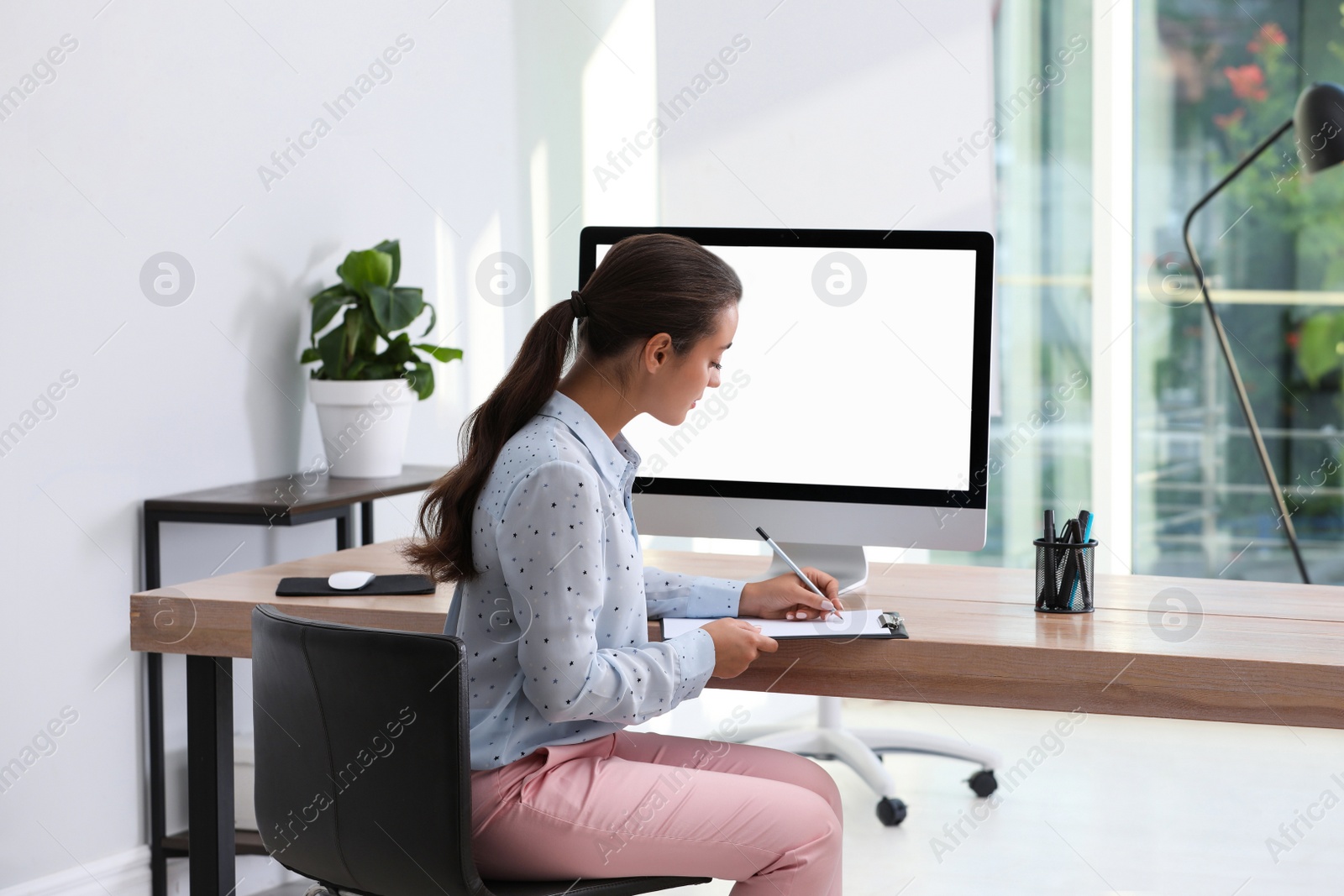 Photo of Young woman working at table in modern office