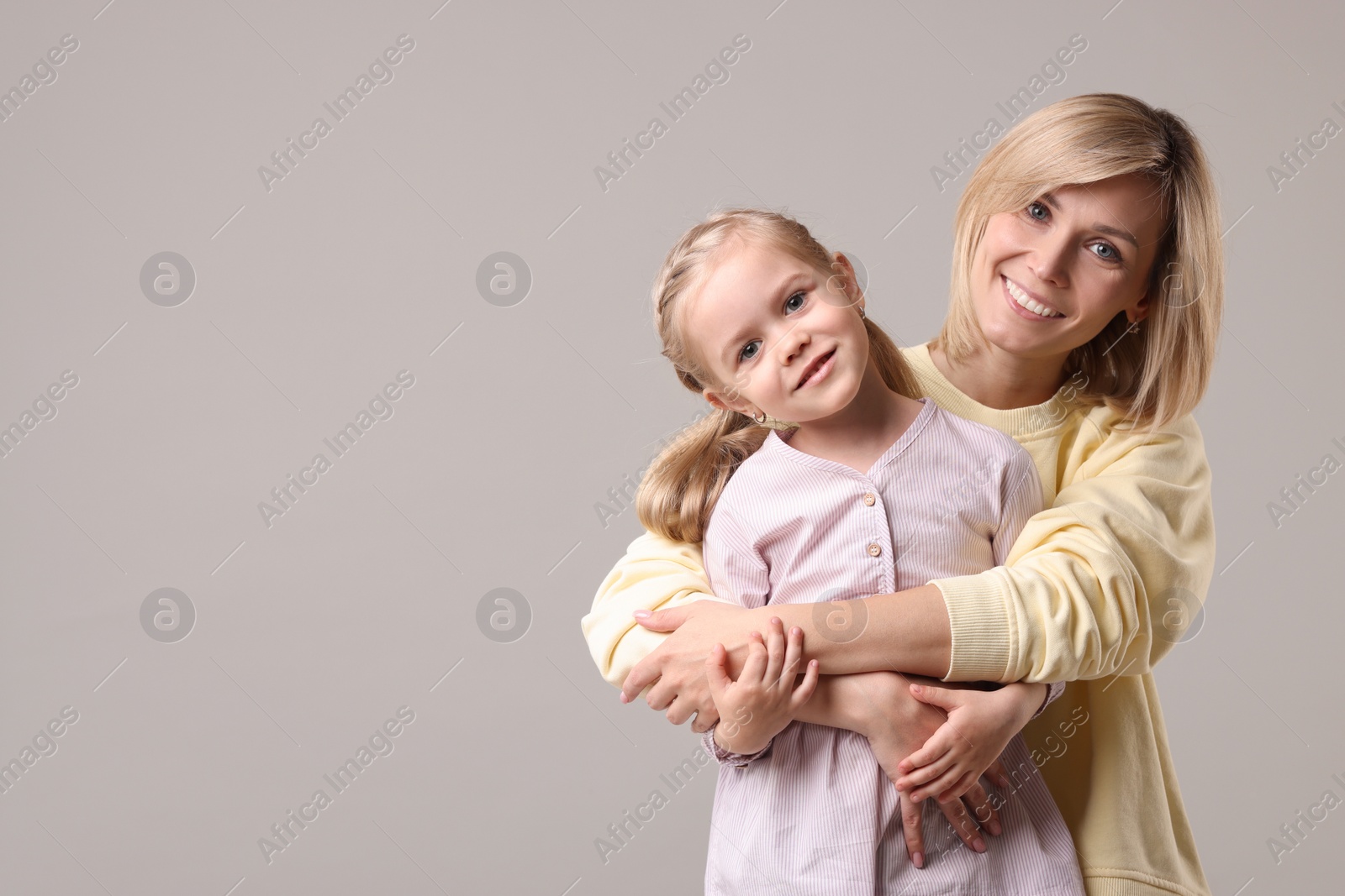 Photo of Family portrait of happy mother and daughter on grey background. Space for text