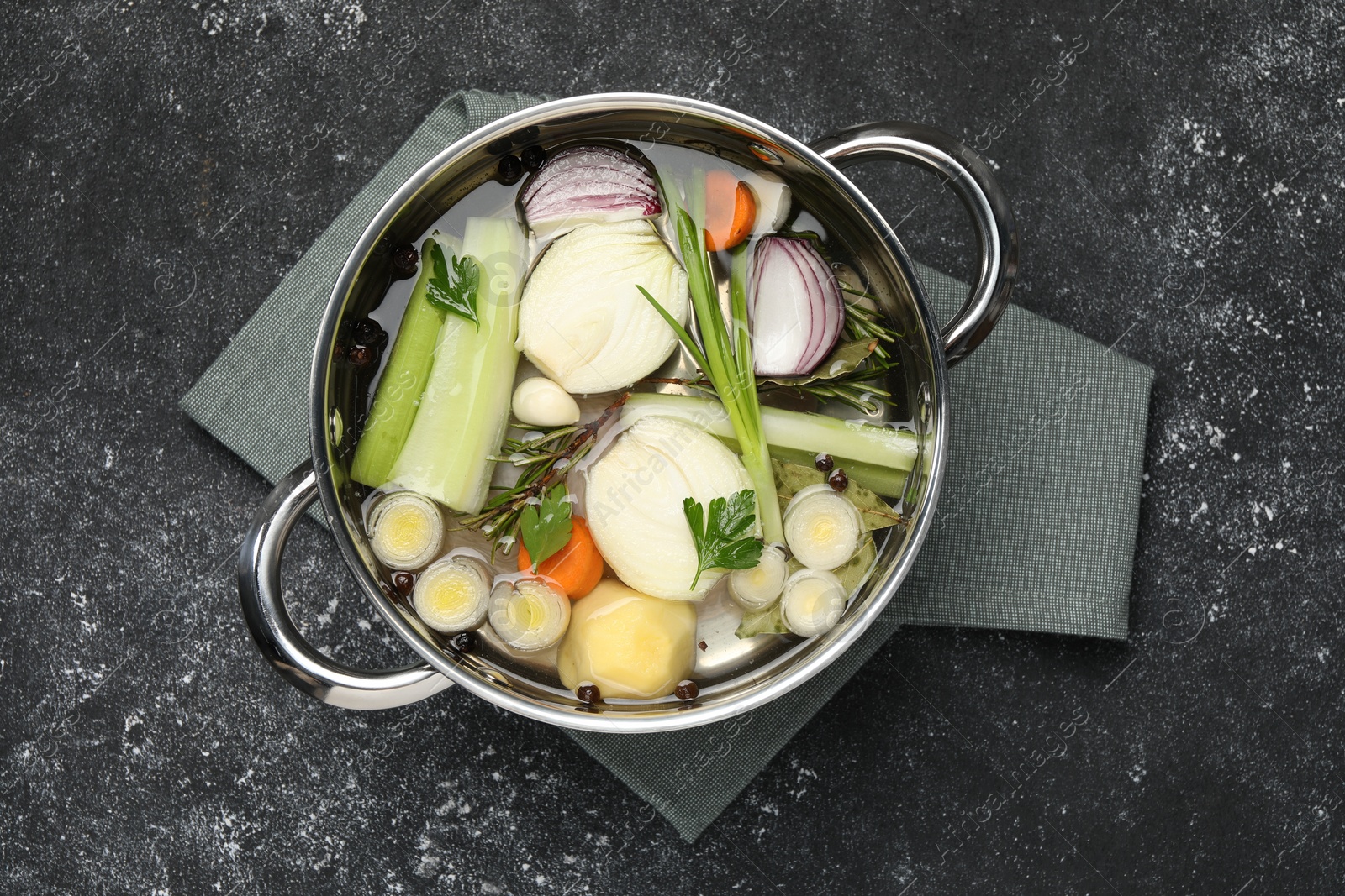 Photo of Different ingredients for cooking tasty bouillon in pot on black table, top view
