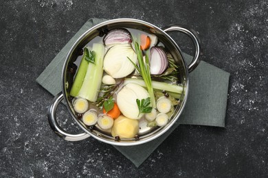 Different ingredients for cooking tasty bouillon in pot on black table, top view