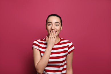 Photo of Beautiful young woman laughing on maroon background. Funny joke
