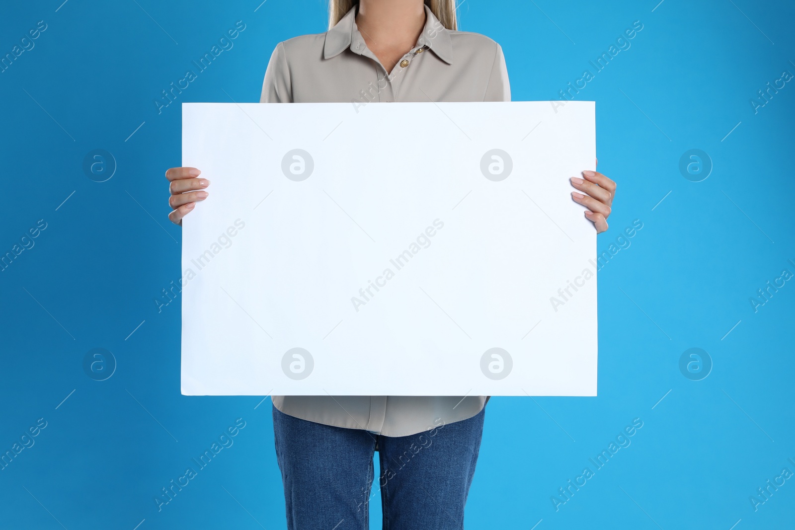 Photo of Woman holding blank poster on blue background, closeup