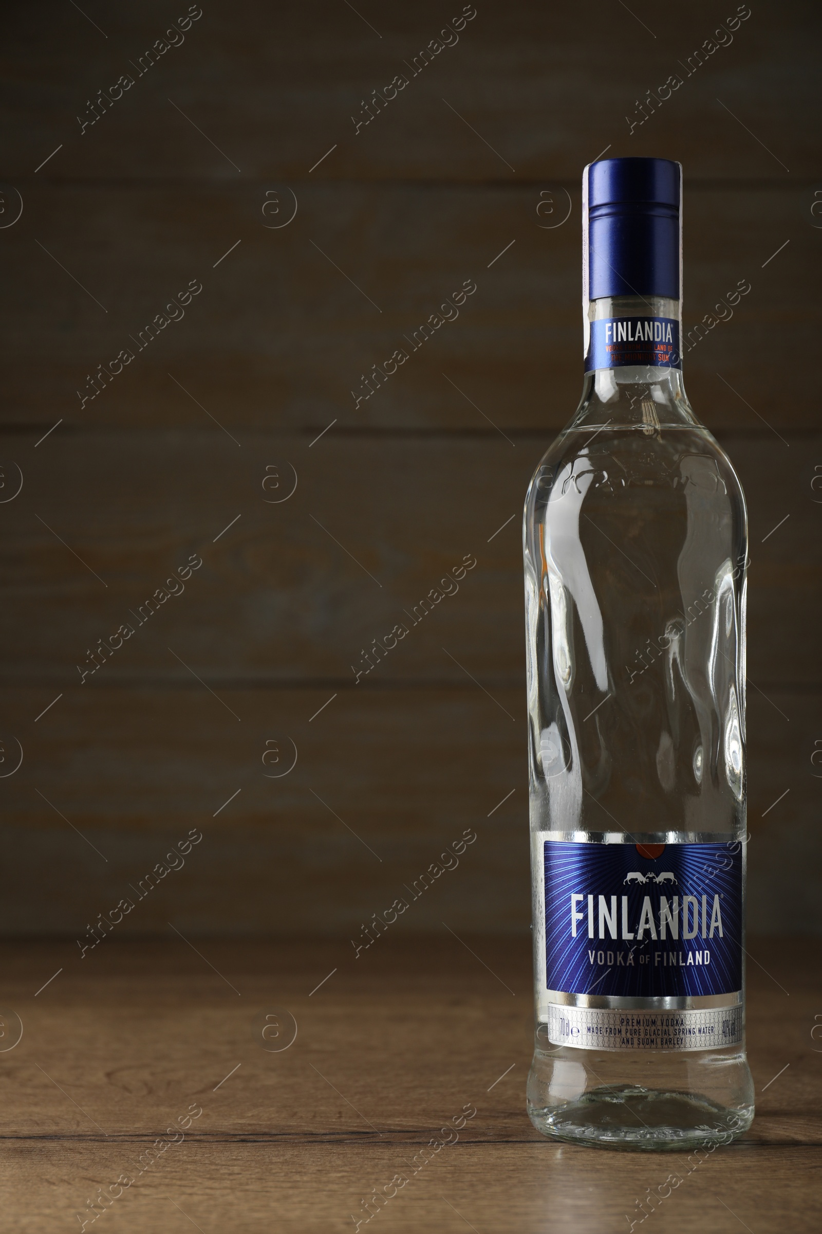 Photo of MYKOLAIV, UKRAINE - OCTOBER 03, 2019: Bottle of Finlandia vodka on table against wooden background. Space for text