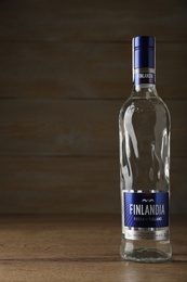 Photo of MYKOLAIV, UKRAINE - OCTOBER 03, 2019: Bottle of Finlandia vodka on table against wooden background. Space for text