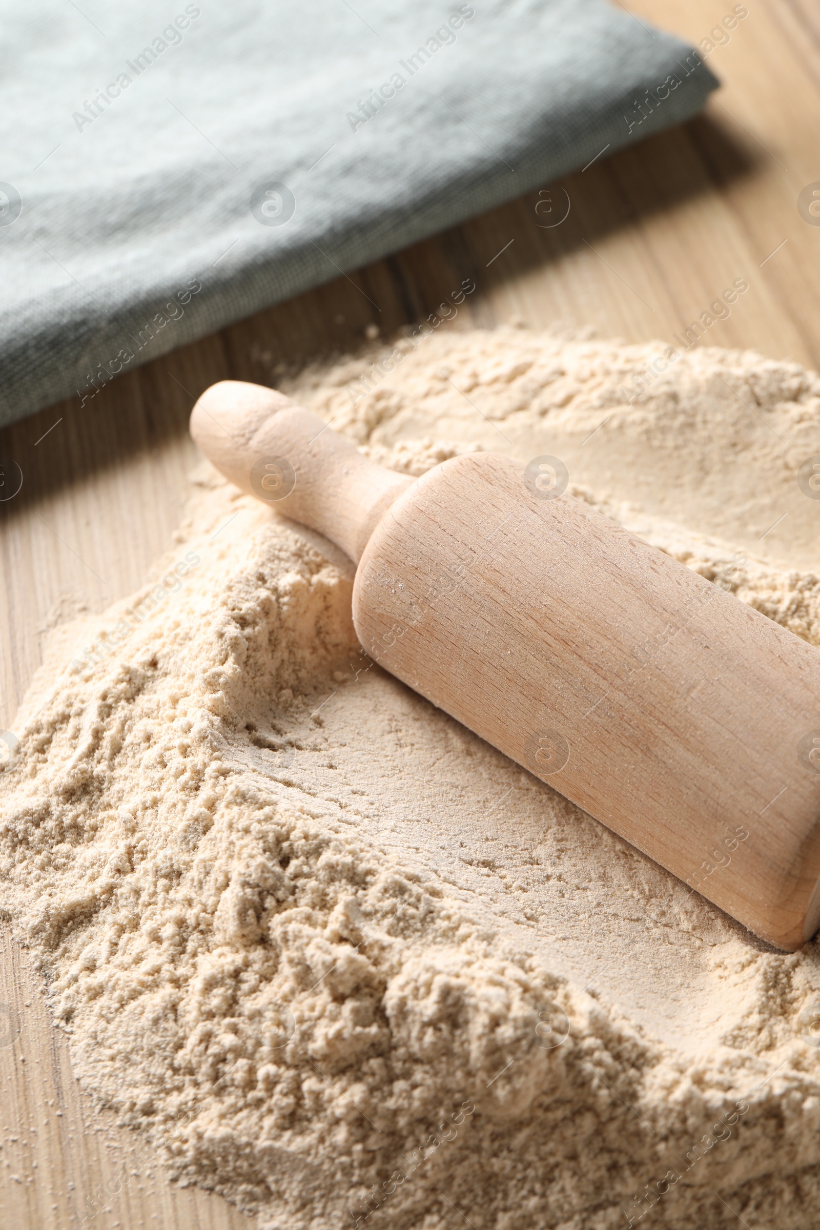 Photo of Pile of flour and rolling pin on wooden table, closeup