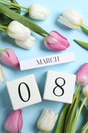 Photo of International Women's day - 8th of March. Block calendar and beautiful tulips on light blue background, flat lay