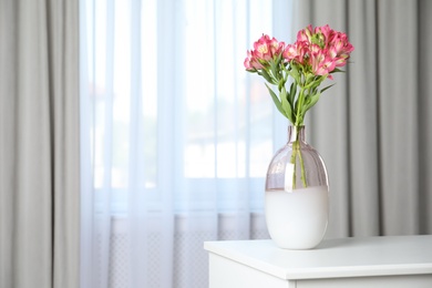 Photo of Vase with beautiful alstroemeria flowers on table near window indoors, space for text. Stylish element of interior design
