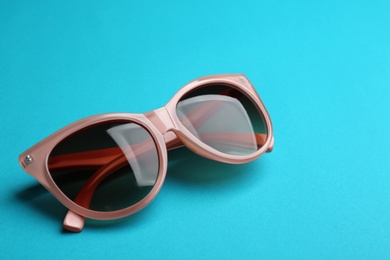 Photo of Stylish sunglasses on blue background. Fashionable accessory