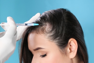 Photo of Young woman with hair loss problem receiving injection on color background, closeup