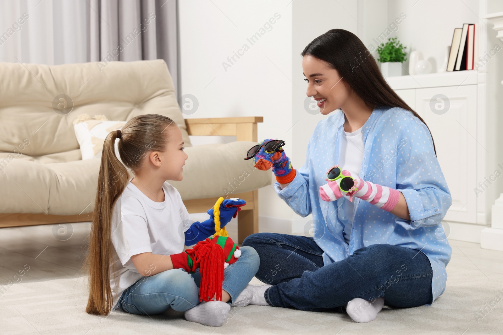 Photo of Happy mother and daughter playing with funny sock puppets together at home