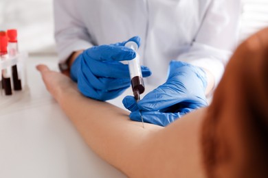 Photo of Nurse drawing blood sample from patient in clinic, closeup