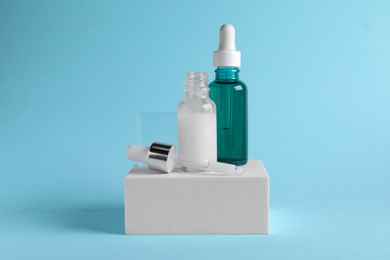Stylish presentation of cosmetic serum on light blue background