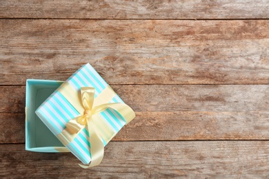 Elegant gift box with bow on wooden background, top view