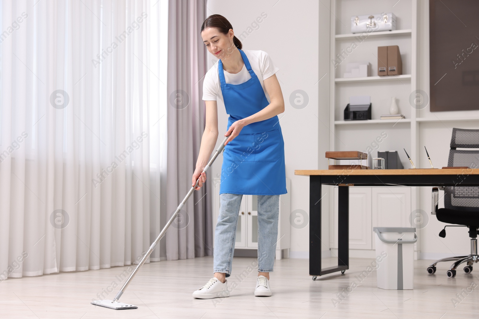 Photo of Cleaning service. Woman washing floor with mop in office