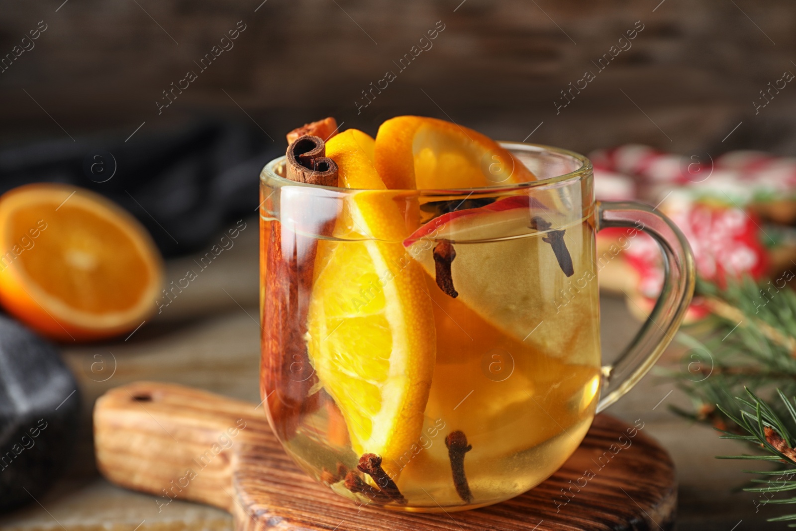 Photo of Aromatic mulled wine on wooden board, closeup