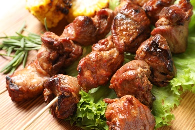 Photo of Barbecued meat with garnish on wooden background, closeup