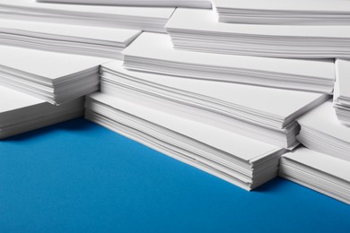 Photo of Many stacks of paper sheets on blue background, closeup