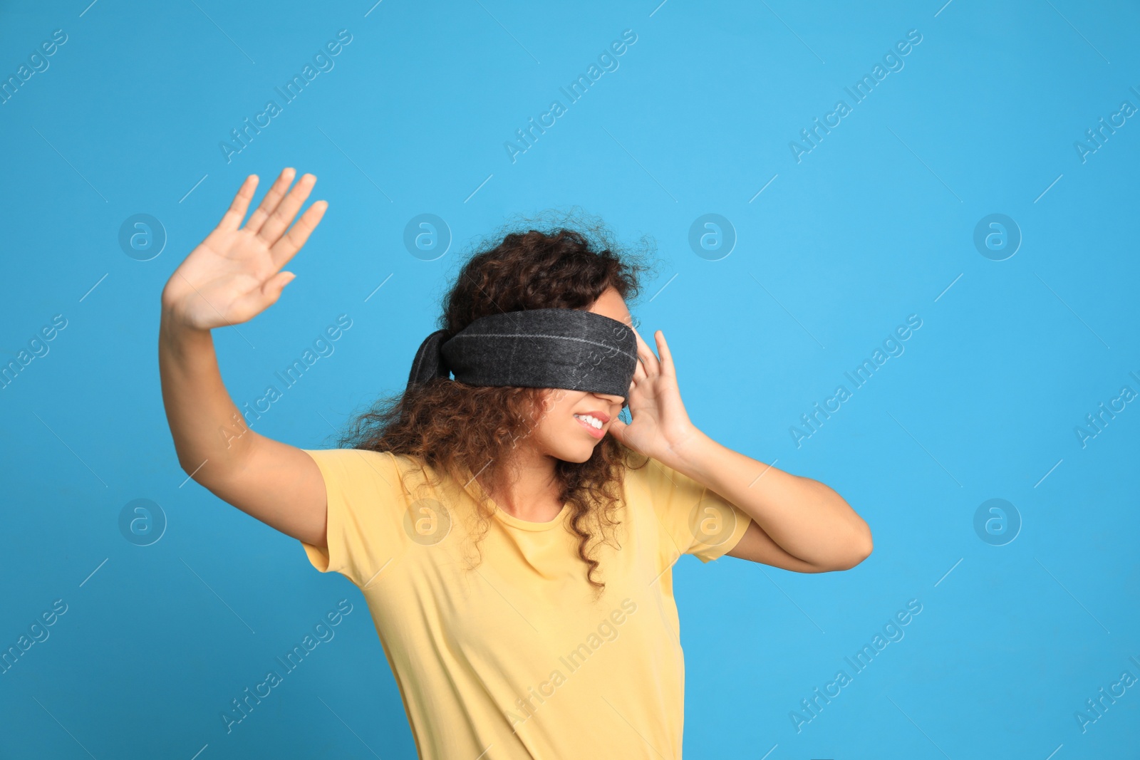 Photo of Young African-American woman with black blindfold on blue background