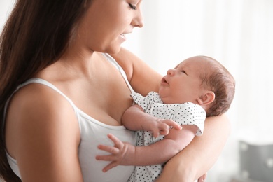 Young woman with her newborn baby on blurred background